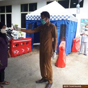 Seorang petugas pelayanan pajak kendaraan Samsat Sawahlunto melakukan cek suhu badan wajib pajak. Foto Iyos