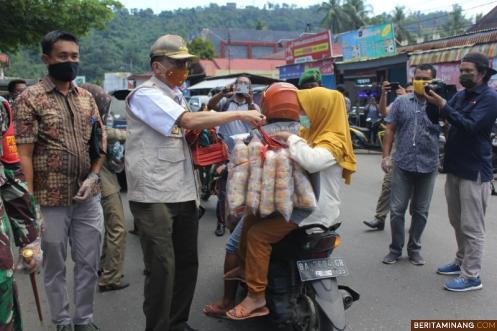 Bupati Hendrajoni bagikan masker pada pengendara di jalan dalam kampanye pemakaian masker di Painan. Foto Humas Pessel
