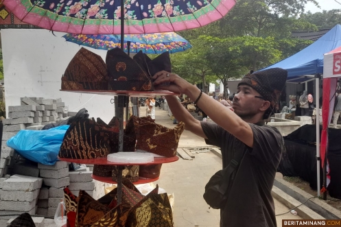 Penjual Deta (topi khas Minangkabau) sedang menata daganganan di arena Festival Pesona Minangkabau (FPM) 2024 di halaman belakang Istano Basa Pagaruyung, Sabtu (7/12/2024). Foto-Foto: Rokcalva/Beritaminang